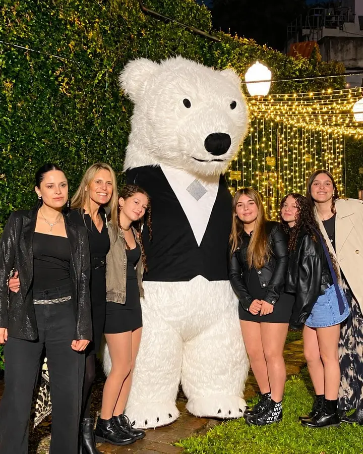 Oso polar gigante de chaleco con invitadas en un jardín de noche